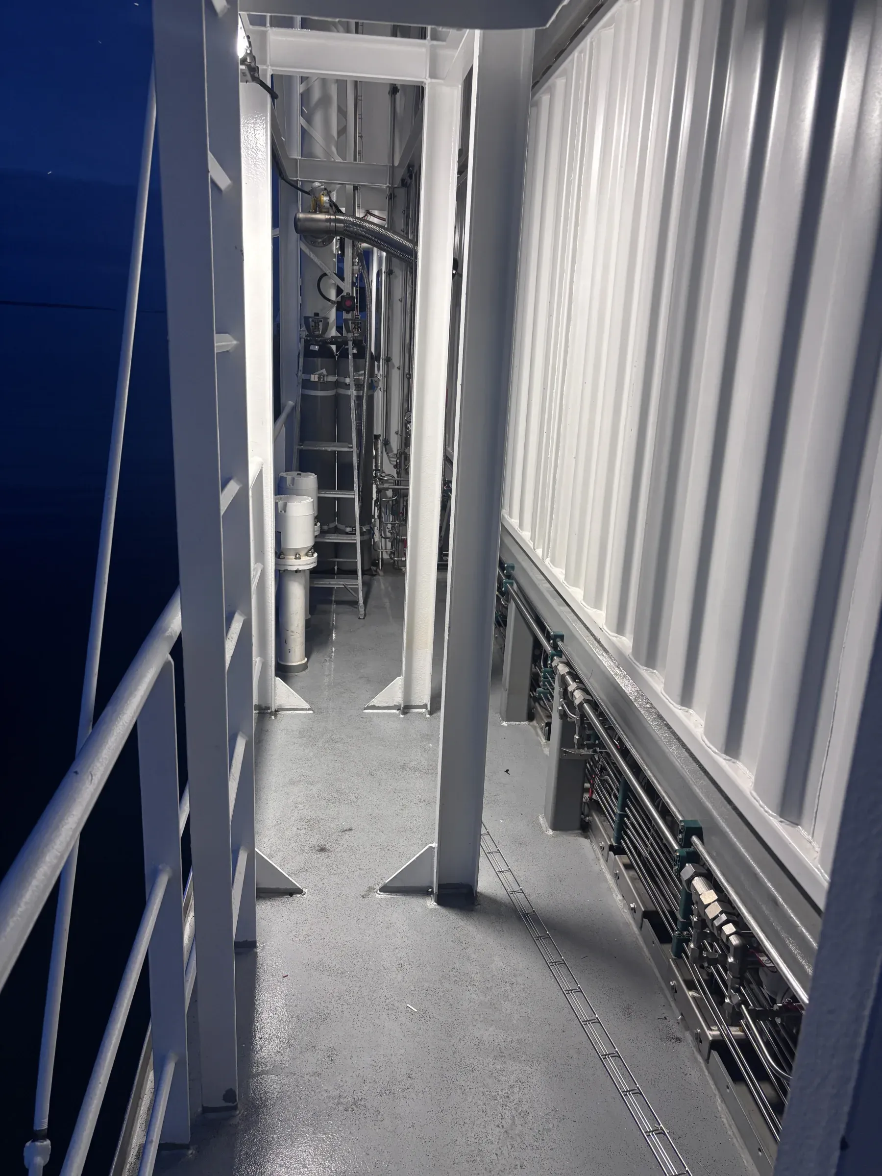 Access corridor inside a containerised CNG pressure-reduction station with visible pipework and instrumentation