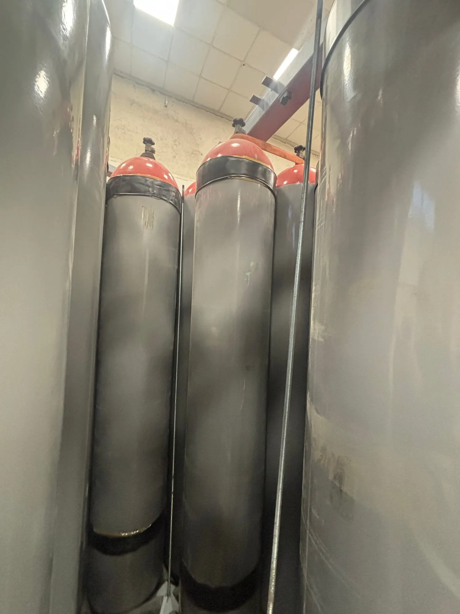 Close-up of steel gas cylinders with their valves inside a container frame